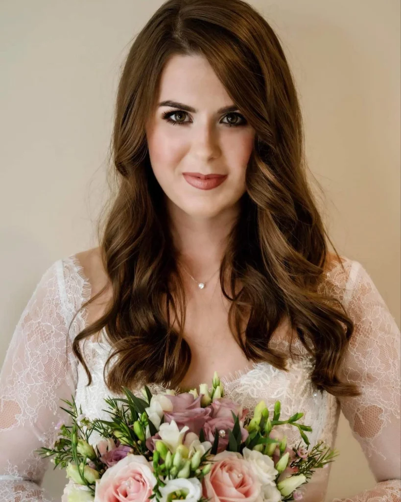 Bride with long waves and classic bridal makeup holding a bouquet.