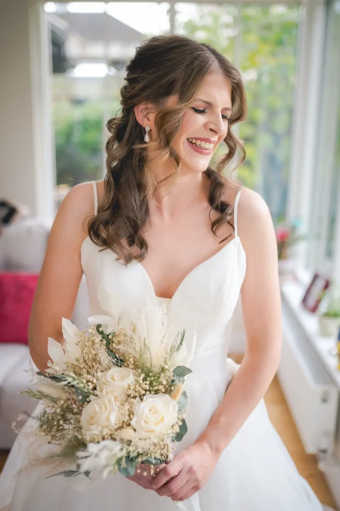 Bride smiling and holding flowers- showing of stunning wedding makeup