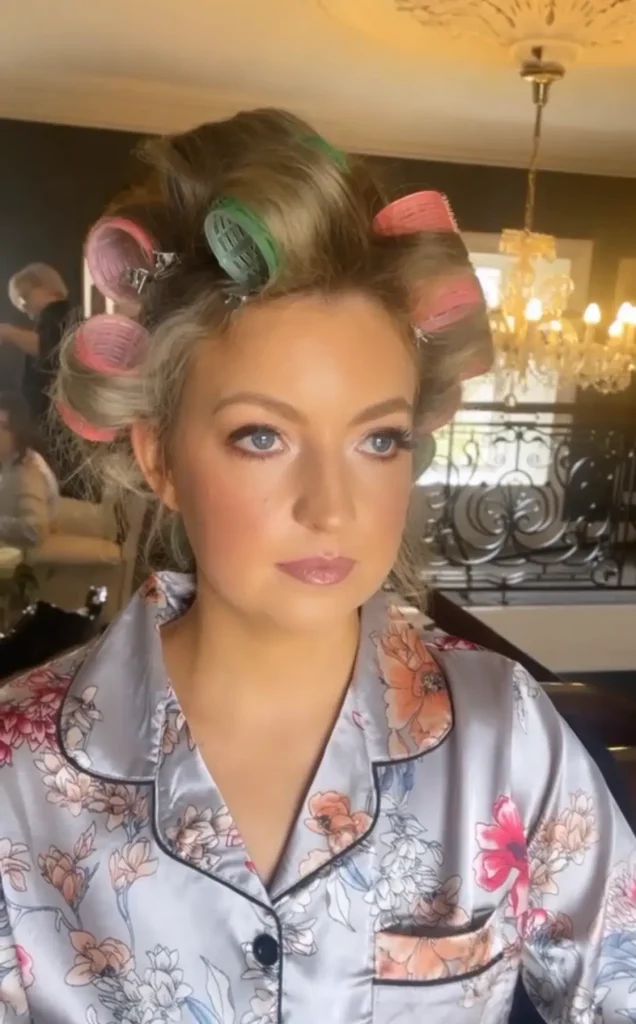 Woman with rollers in her hair, sitting for her makeup by Nima