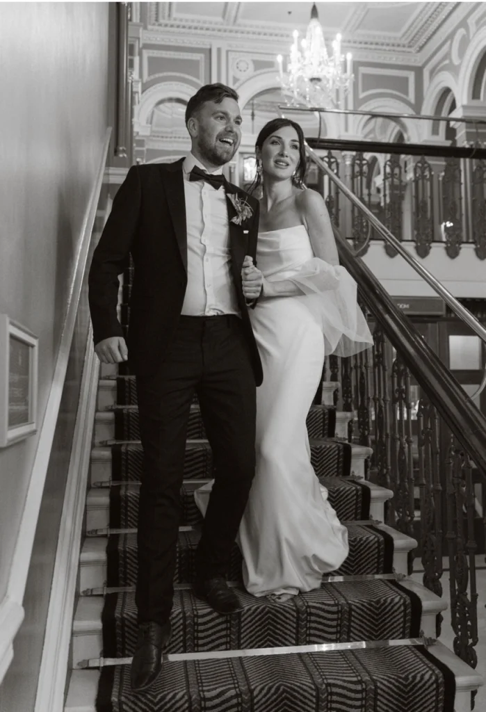 Black and white photo of gorgeous bride and groom walking down a staircase on their wedding day in Ireland