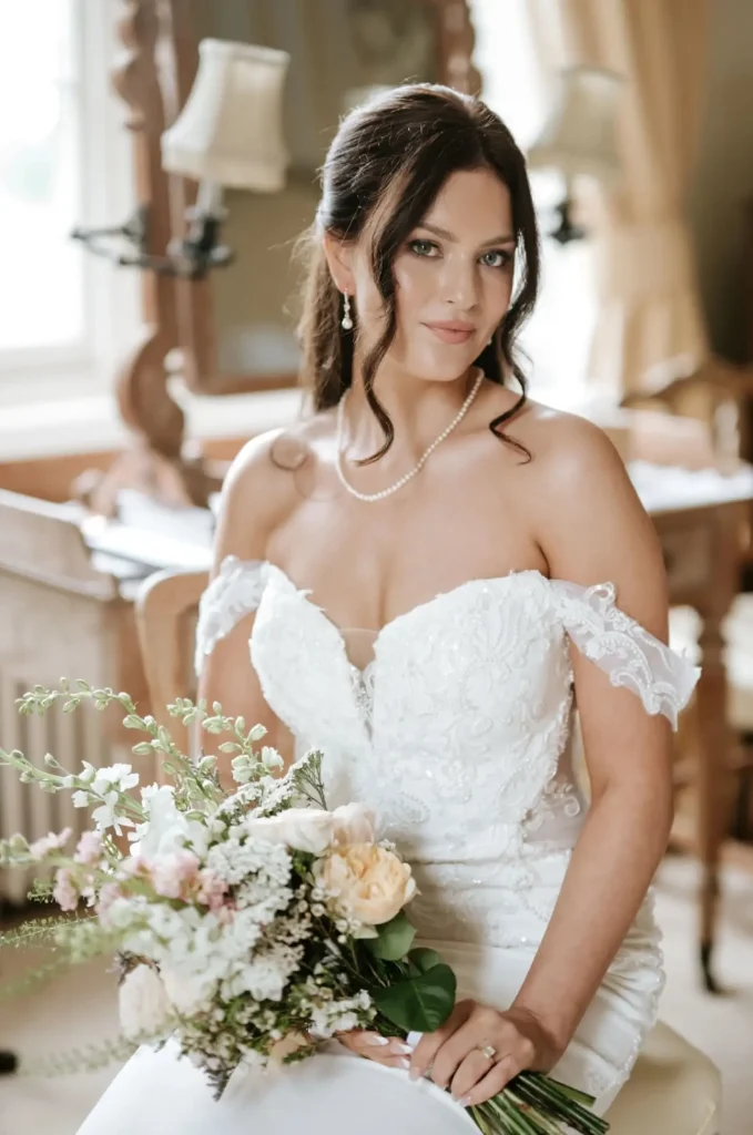 Stunning brunette bride sitting and holding flowers in her hand - bridal makeup artist Nima