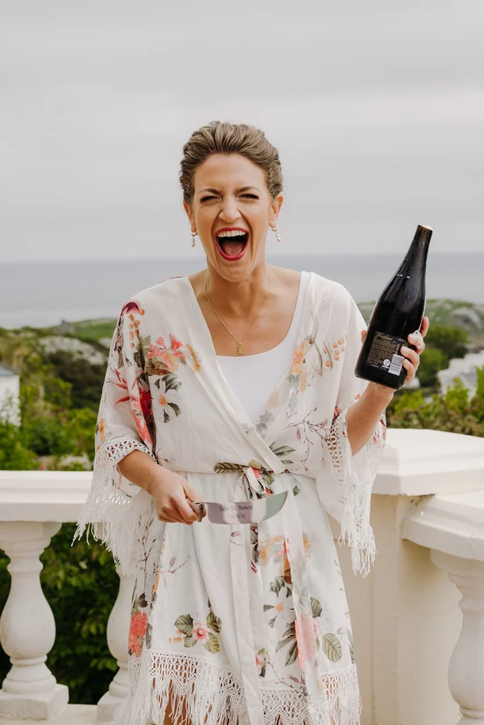 Gorgeous smiling bride after popping open champagne with her wedding makeup untouched