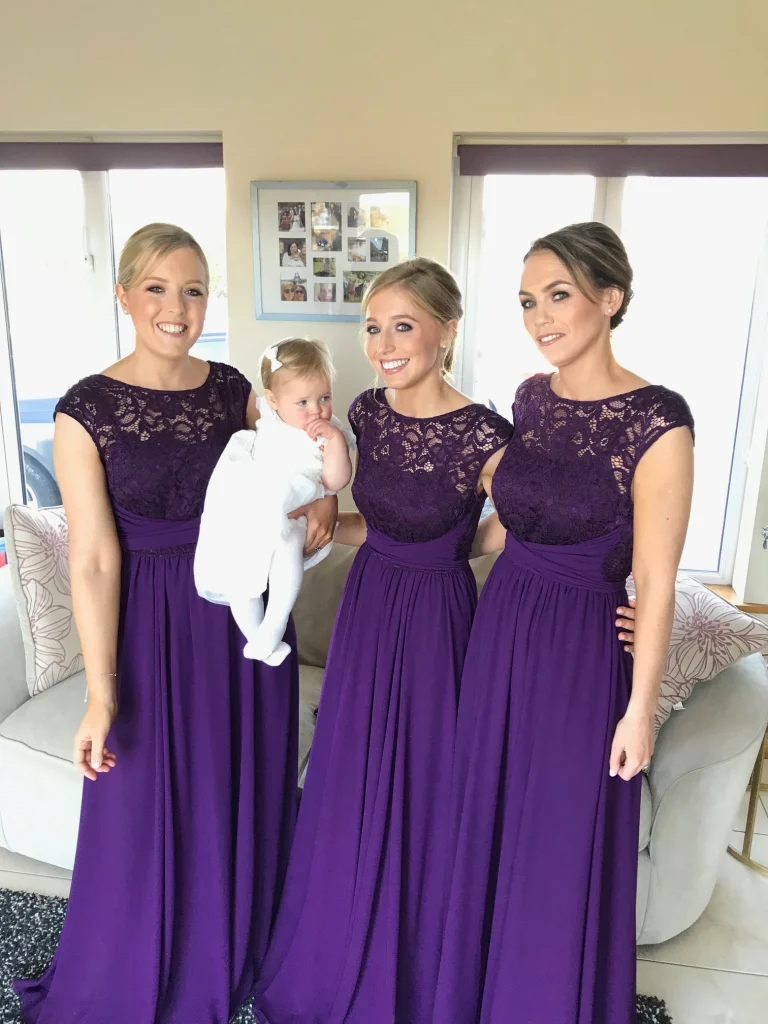 3 stunning bridesmaid in purple dresses - one holding a baby